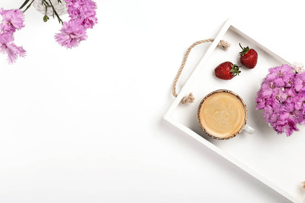Light mockup for product presentation on a white table with a cup of coffee, strawberries and flowers on a tray. - Photo, Image