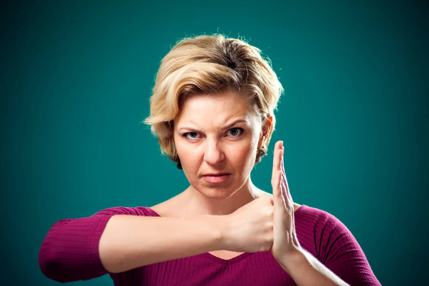 Mujer enojada con el pelo corto y rubio mostrando puños en la cámara. Concepto de personas, estilo de vida y emociones - Foto, imagen