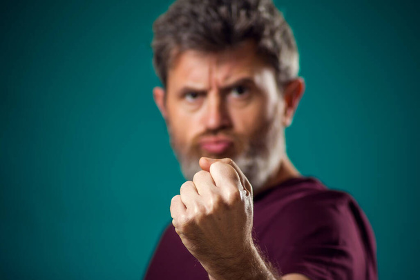 Un retrato de un hombre barbudo enojado con una camiseta roja mostrando el puño en la cámara. Peopel y el concepto de emociones - Foto, imagen