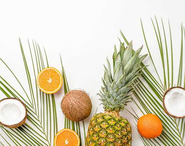 Sommerhintergrund mit frischen Orangen, Kokosnüssen und Ananas auf hellgrauem Hintergrund - Foto, Bild