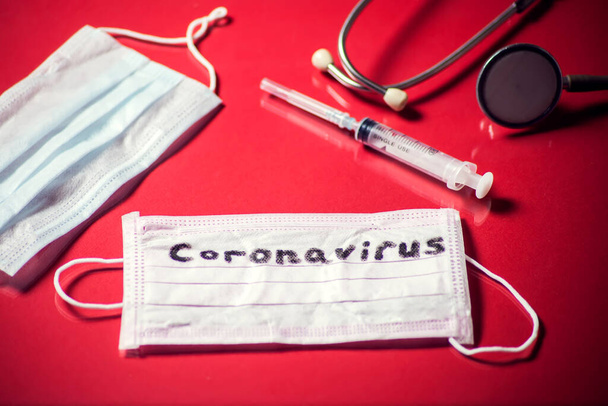 Máscara com palavra-coronavírus, itens de medicina em fundo vermelho. Conceito de Medine e saúde - Foto, Imagem