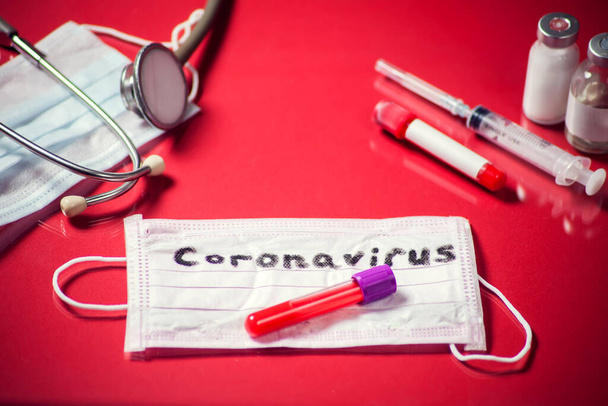 Masker met woord-coronavirus, medicijnen op rode achtergrond. Begrip "geneeskunde en gezondheidszorg" - Foto, afbeelding