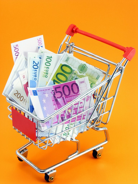 オレンジ色の背景にショッピング トロリーでユーロ通貨 - 写真・画像
