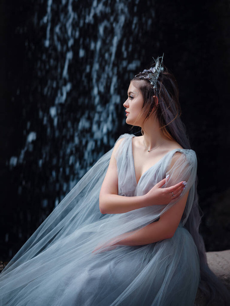 a beautiful woman like a fairy or nymph walking in the park. fairy tale image art photo. beautiful portrait in the darkness of the park, the waterfall jets like wings - Foto, Imagen