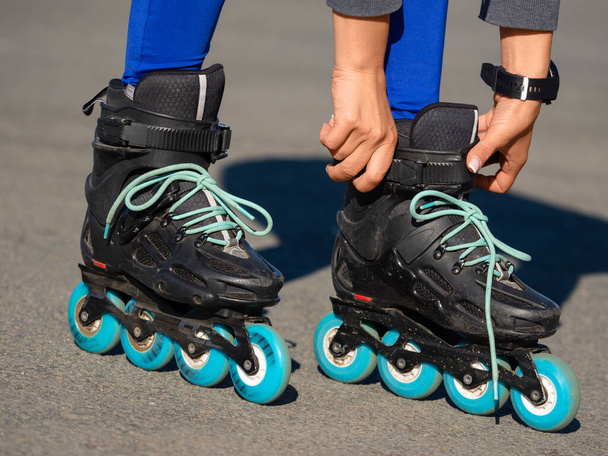 Close-up of an Anonymous Womans Hands Fixing Laces on Roller Blades Before Skating. - Foto, imagen