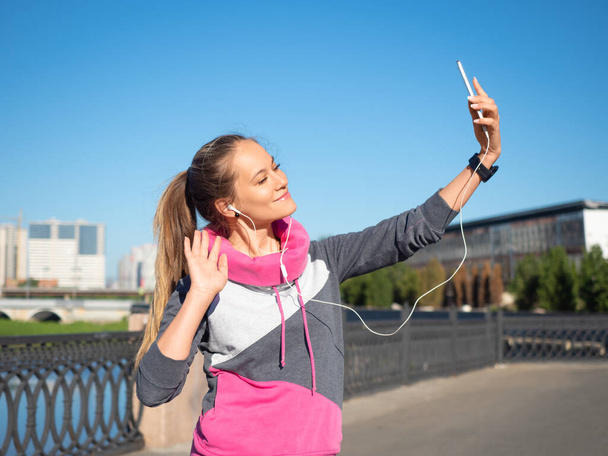 若い女性が朝ジョギング中にスマートフォンを使って自撮りをする。健康的なライフスタイルの概念とフィット感を保つ. - 写真・画像