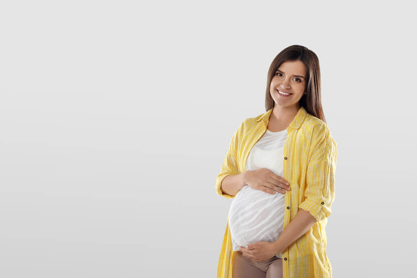 Happy young pregnant woman on white background, space for text - Фото, изображение