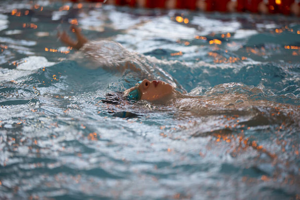 Ragazzo in cuffia e occhiali da nuoto in piscina. Il bambino è impegnato nella sezione di nuoto. - Foto, immagini