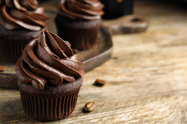Delicious chocolate cupcake with cream on wooden table, closeup. Space for text - Фото, зображення