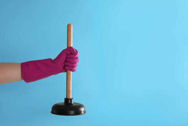 Woman holding plunger on turquoise background, closeup. Space for text - Foto, immagini