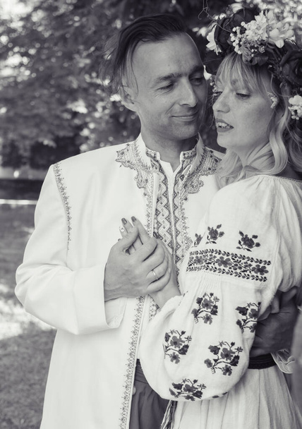 A fiatalok hagyományos népviseletben pózolnak. Kozák férfi és nő koszorúban és hímzett ingben. Vintage hagyományok és szokások újjáépítése. Pasi és lány csók - Fotó, kép