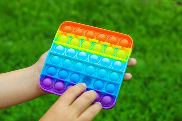 Dětské ruce se hrají čtvercové vícebarevné bublina hračka antistress smyslové pop to. - Fotografie, Obrázek