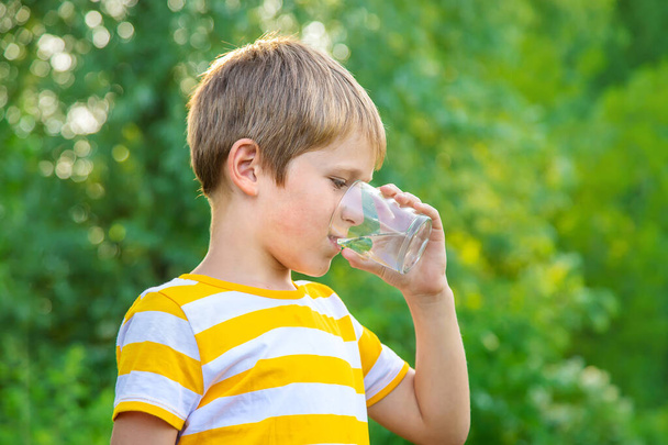 Chlapec pije vodu ze sklenice. Selektivní soustředění. Kluk. - Fotografie, Obrázek