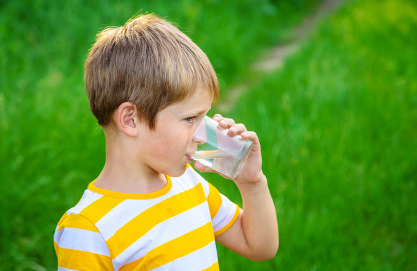 El niño bebe agua de un vaso. Enfoque selectivo. Niño.. - Foto, Imagen