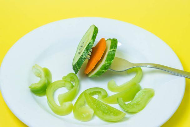 黄色の背景に皿の中で野菜をスライス.新鮮な野菜から作られた健康的な食事食品。ベジタリアンフード - 写真・画像