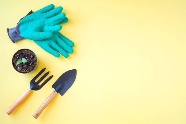 composición de herramientas de jardinería y guantes verdes sobre fondo amarillo  - Foto, imagen