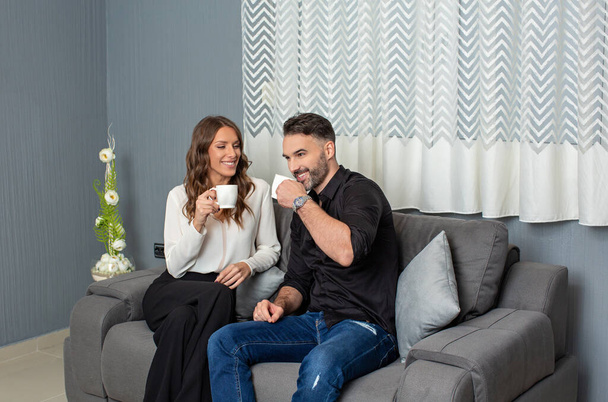 Happy couple drinking coffee sitting on the sofa - Fotó, kép