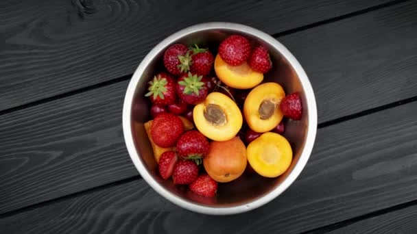 Aprikosenerdbeeren gewaschen Schalen auf schwarzem Holzhintergrund. Rotierender Hintergrund - Filmmaterial, Video