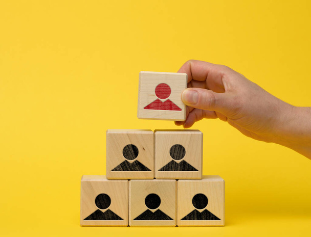 female hand holds a wooden block on a blue background. Recruitment concept, teamwork, effective management. CEO search, yellow background - Photo, Image