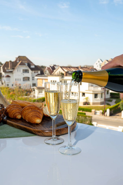 Drinking of brut champagne sparkling wine in flute glasses on outdoor cafe or bistro terrace in France on sunny day - Photo, Image