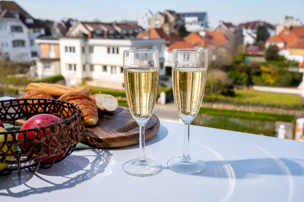 Boire du champagne brut mousseux dans des verres à flûte sur une terrasse de café ou de bistrot en France par une journée ensoleillée - Photo, image