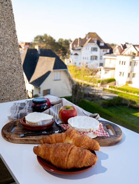 Colazione francese con croissant appena sfornati e formaggi della Normandia, camembert e neufchatel servita all'aperto con bella vista sul villaggio francese - Foto, immagini