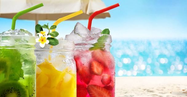 Sommer erfrischende exotische Drinks Cocktails in Glasgefäßen mit Strohhalmen auf Meereslandschaft mit Bokeh-Sonnenlicht Hintergrund. - Foto, Bild