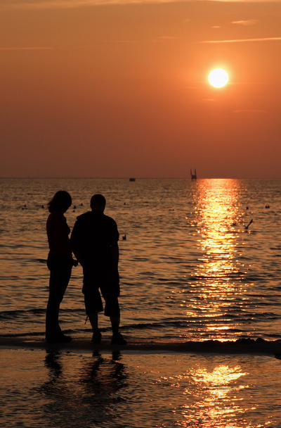 jongen en meisje bij zonsondergang op het water - Foto, afbeelding