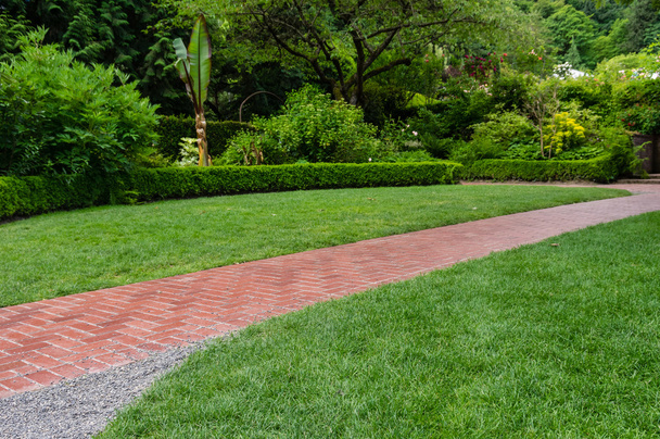 Brick walkway leading through a garden - Фото, зображення