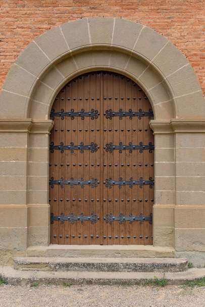 Puerta de madera con acabados de hierro negro y un arco de piedra - Foto, Imagen