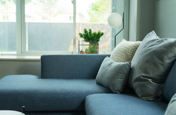 blaue, weiße und graue Kissen auf blauem Sofa im Wohnzimmer des modernen Hauses. - Foto, Bild