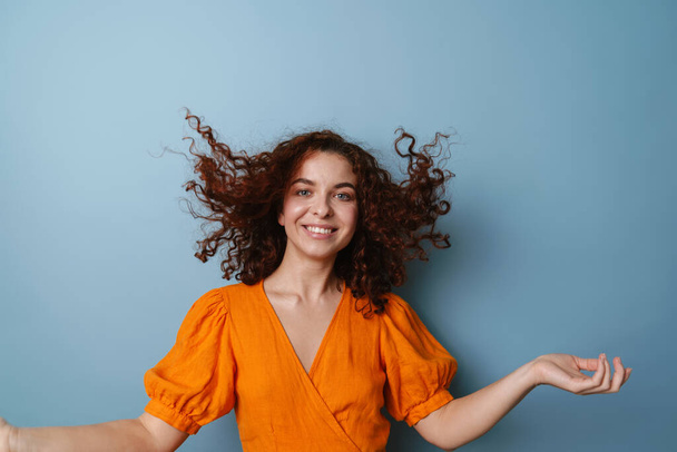Joyful ginger young woman making fun with her hair isolated over blue background - Foto, Imagen