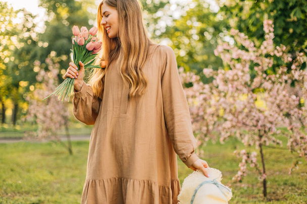 Portrait of a beautiful young woman in a flowering apple tree garden in springtime, enjoying nature, spring concept, Beautiful girl in the garden - Zdjęcie, obraz
