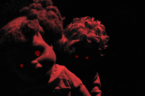 Horror red toned photo of scary possessed plastic dolls with glowing red eyes on dark background. - Photo, Image