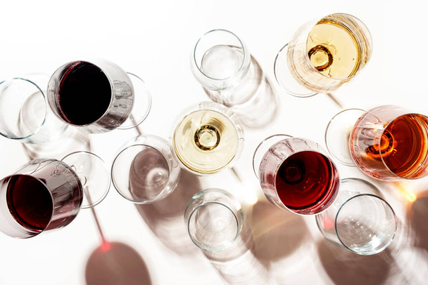 Red, rose and white wine in glasses on white background, top view. Wine bar, shop, winery, wine tasting concept. Hard light and harsh shadows - Valokuva, kuva