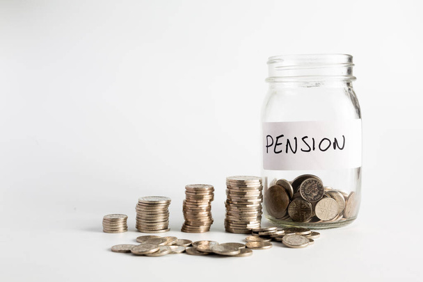 Mince naskládané vedle prázdné sklenice s nálepkou pro penzijní fond. Důchod, finanční, úspory, ekonomika, investiční koncepce - Fotografie, Obrázek