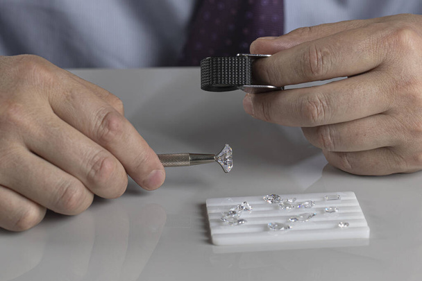 Close up of diamond dealers hands evaluating diamond at international jewelry exhibition - Fotografie, Obrázek
