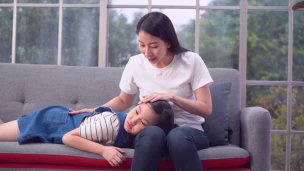 Η μητέρα παρηγορεί ένα αναστατωμένο παιδί ξαπλωμένο στην αγκαλιά της σε έναν καναπέ.. - Πλάνα, βίντεο
