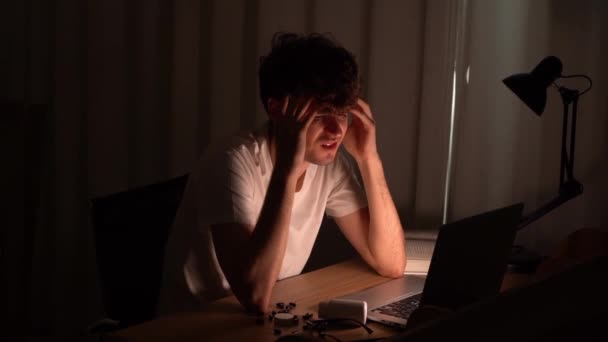 uitgeput man is moe werken op laptop computer tijdens het werken thuis in quarantaine periode laat op de avond. - Video