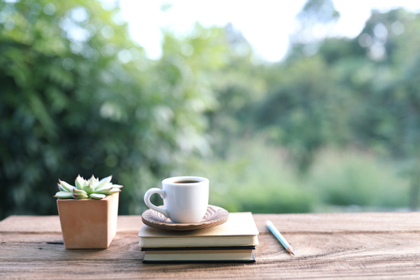 Μικρό λευκό φλιτζάνι καφέ και γλάστρα σε καφέ ξύλινο τραπέζι - Φωτογραφία, εικόνα
