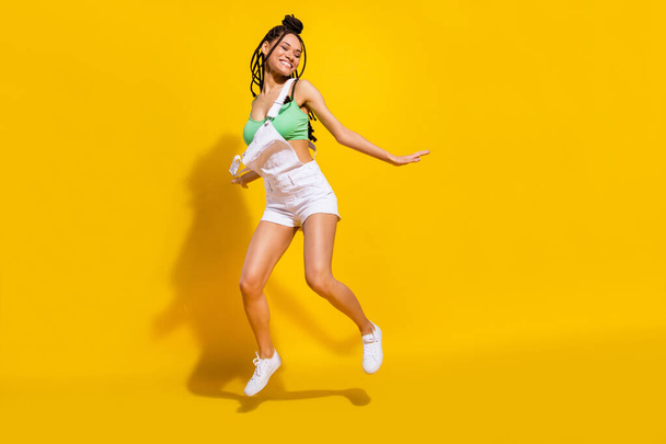 Full size photo of afro american charming happy young woman jump up good mood dance isolated on yellow color background - Foto, imagen