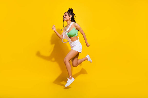 Full length photo of brunette afro american young woman jump up run empty space isolated on yellow color background - Zdjęcie, obraz