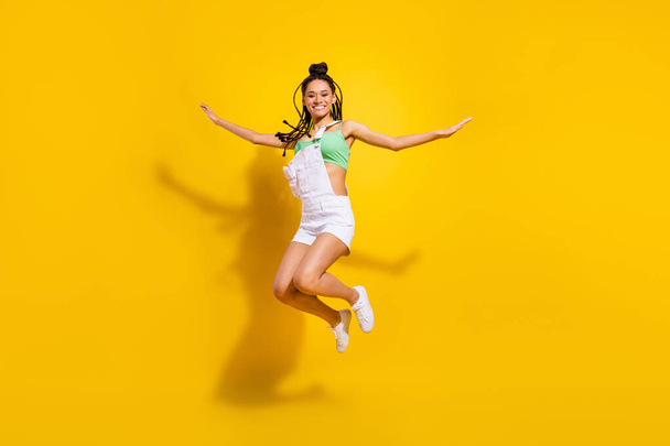 Full body photo of afro american young attractive woman jump up hands wings isolated on yellow color background - Фото, изображение