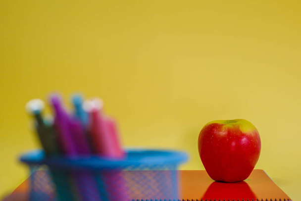 School supplies, notebook and fruit over a yellow backgroud. Copy space and selective focus - Fotoğraf, Görsel