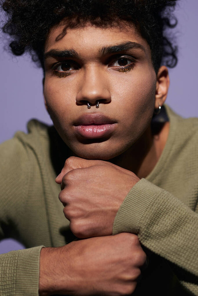 Close up portrait of young afroamerican man face on arms. Sexy transgender male with pirsing in nose - Foto, afbeelding
