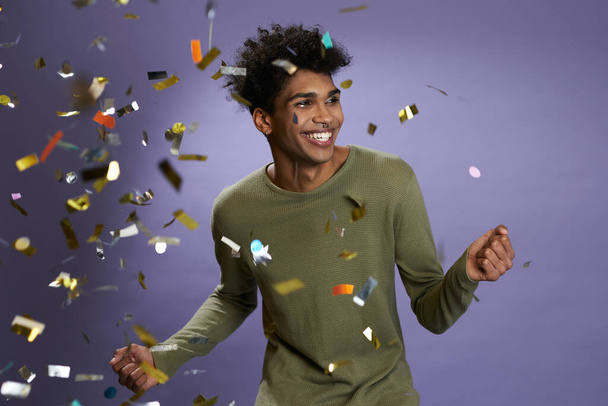 Joven afroamericano alegre bailando con retrato de confeti dorado. Ríe y sonríe transgénero - Foto, imagen