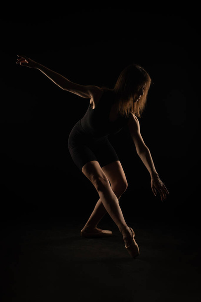 Silhouette of ballerina posing with her posture down - Fotó, kép