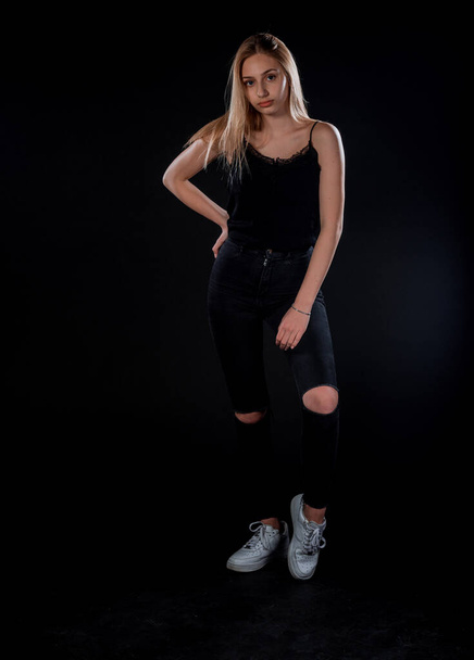 Vonzó fiatal női modell pózol fekete felső és fehér tornacipőben - Fotó, kép