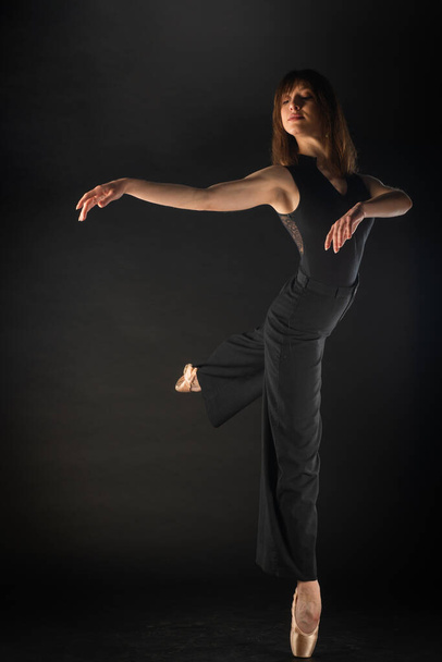 Mooie ballerina doet een perfecte ballet pose op zwarte achtergrond - Foto, afbeelding