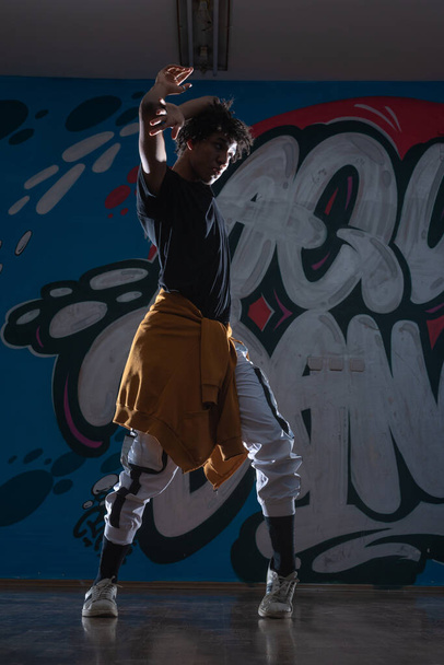 アフリカ系アメリカ人ヒップホップダンサー(ブレイクダンサー)が黒のシルエット露出で落書きを背景に演奏. - 写真・画像